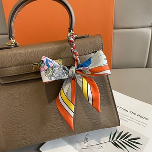 Foulard en soie imprimé coloré enroulé sur la poignée d'un sac à main en cuir brun