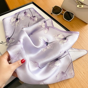 Gros plan détaillé du foulard en soie violet clair à motif floral et texture satinée