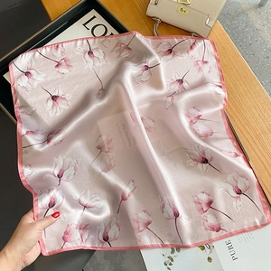 Détail d'un foulard en soie avec imprimé tulipe et couture fine sur une table en bois