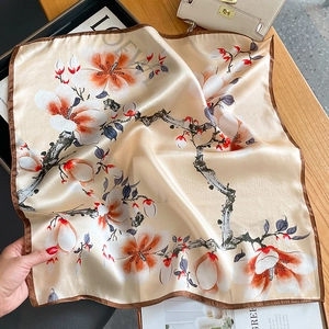 Elegant champagne silk square scarf featuring magnolia flower prints on a wooden desk