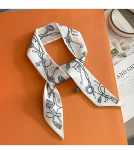 Detail of elegant white twilly scarf with vintage key patterns on a classic orange box