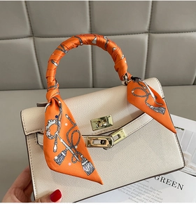 Detail of silk scarf wrapped around a cream lychee grain leather handbag handle