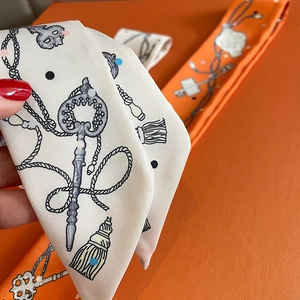 Macro shot of silk twilly scarf with classic key pattern and orange textured reverse
