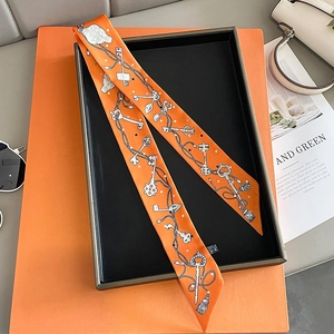 Close-up of a bright orange silk twilly scarf with vintage key and chain patterns