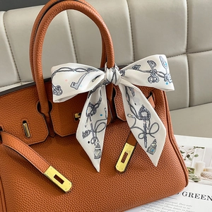 Brown litchi leather handbag with gold buckle and a decorative printed silk scarf tie