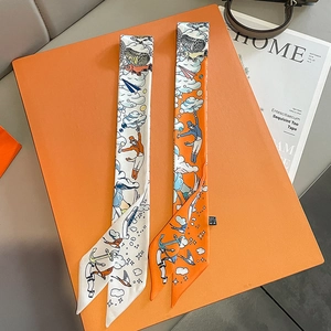 Narrow silk scarves with hand-drawn illustrations displayed on an orange luxury gift box