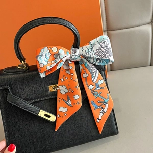Classic black pebbled leather handbag with decorative orange printed silk scarf wrap