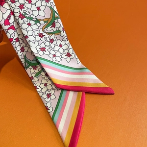 Detail eines Seidenschals mit Blumendruck und Regenbogenstreifen auf orangefarbenem Grund