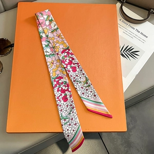 Seidenschal mit Blumenmuster auf einer luxuriösen Lederbox und einer Handtasche