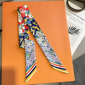 Detail eines Seidenschals mit Blumenmuster und Regenbogenrand auf einer Geschenkbox