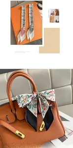 Detailed view of floral silk twilly scarf wrapped on leather handbag handle