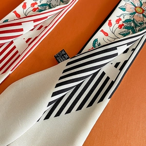 Detail of floral skinny scarf with red berries over a textured orange gift box