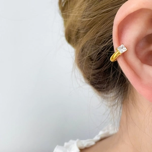 Gros plan d'une manchette d'oreille dorée avec zircon carré et fini miroir poli
