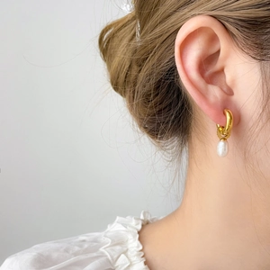 Gros plan d'une boucle d'oreille en or avec pendentif perle d'eau douce sur un mannequin
