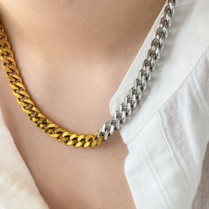 Detail of two-tone gold and silver curb link necklace on white textured shirt