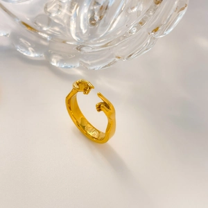Detailansicht eines vergoldeten Rings mit Händedruck-Motiv von oben auf weißem Grund