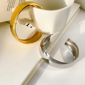 Detailed view of polished C-shaped open bangles in gold and silver mirror finish