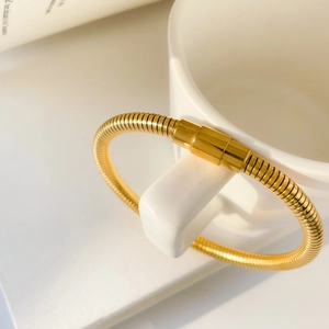 Detail of golden snake bone texture bracelet hanging on a white porcelain handle