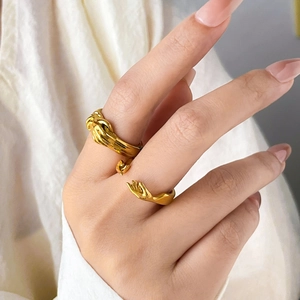Detailansicht von Handform-Ring und gedrehtem Goldband, getragen von einem Modell