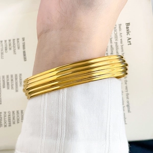 Polished gold snake chain cuff bracelet with ribbed texture shown on a model's wrist