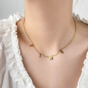 Détail du collier en titane plaqué or 18 carats avec pendentifs lettres 'FINE'