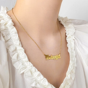 Gros plan du collier Babygirl en acier titane doré avec pendentif gothique sur modèle