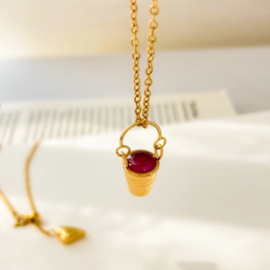 Macro d'un collier doré avec pendentif en zircon rouge et chaîne ajustable en forme de cœur