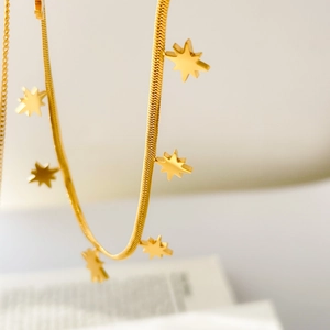 Gros plan de breloques étoiles dorées sur un collier à chevrons en titane sur un livre