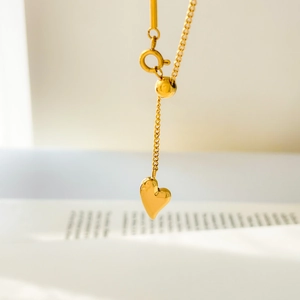Vue macro du pendentif coeur en or 18K avec perle coulissante ajustable et fermoir ressort
