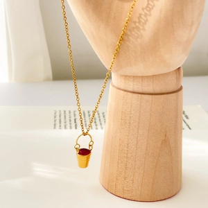 Gros plan du pendentif seau doré serti de zircon rouge sur chaîne gourmette vintage