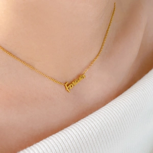 Primo piano della collana dorata con pendente Forever e catena sottile indossata