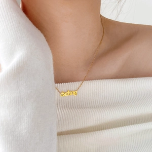 Dettaglio della collana in titanio placcata oro 18K con pendente Darling in corsivo