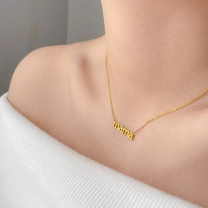 Dettaglio della collana con ciondolo mama dorato placcato oro 18K indossata da una modella