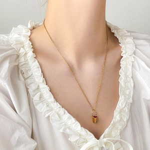 Détail d'un collier doré avec pendentif en zircon rouge sur le cou d'un mannequin