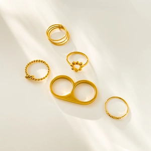 Detailed set of five 18K gold plated titanium rings with knots and flower motifs