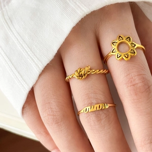 Detailed macro view of 18K gold plated stackable rings featuring MAMA and knot designs