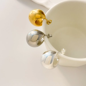 Close-up of minimalist C-shape stud earrings in gold, silver, and gunmetal finishes
