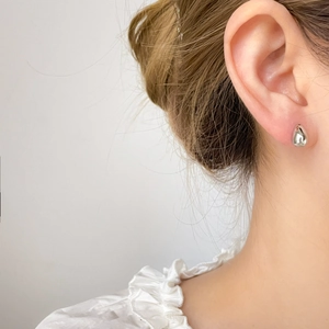Close-up of a minimalist silver teardrop stud earring on a model's earlobe