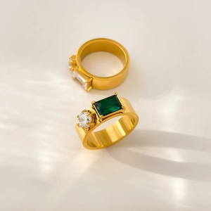 Macro shot of titanium steel rings featuring green emerald-cut zircon and brushed finish