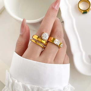 Close-up of gold layered rings with rectangular zircons on model hand with ceramic plate