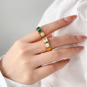 Detail of gold rings set with emerald-cut green stone and sparkling cubic zirconia