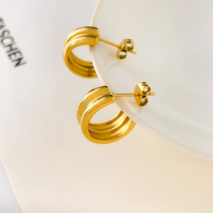 Macro view of C-shaped drop earrings with 18K gold plated ribbed metal texture
