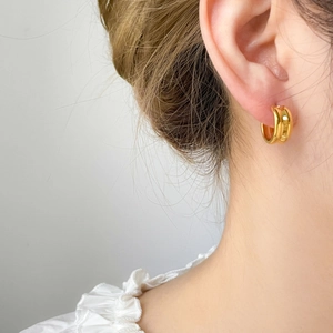 Detailed view of chunky 18K gold plated teardrop hoop earrings on model ear lobe
