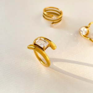 Macro shot of 18K gold plated titanium ring with emerald-cut zircon and curved design