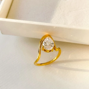 Macro shot of a 18K gold-plated ring featuring a pear-cut cubic zirconia on a wavy band