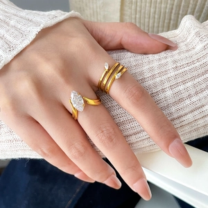 Detail of 18K gold plated marquise zircon stackable rings worn on a hand over knitwear