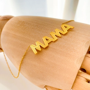 Détail macro du pendentif MAMA doré avec texture verticale sur chaîne plaquée or 18K