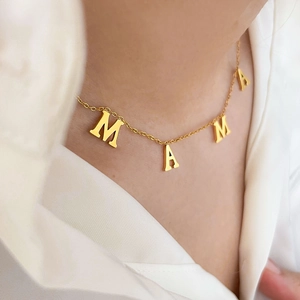Détail du collier MAMA plaqué or 18 carats porté sur une chemise en soie blanche