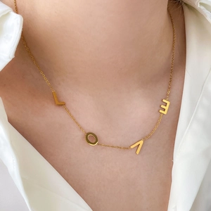 Gros plan d'un collier LOVE en plaqué or 18 carats porté par une femme sur le cou