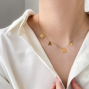 Détail du collier pendentif MAMA doré porté par un mannequin pour un look élégant et raffiné